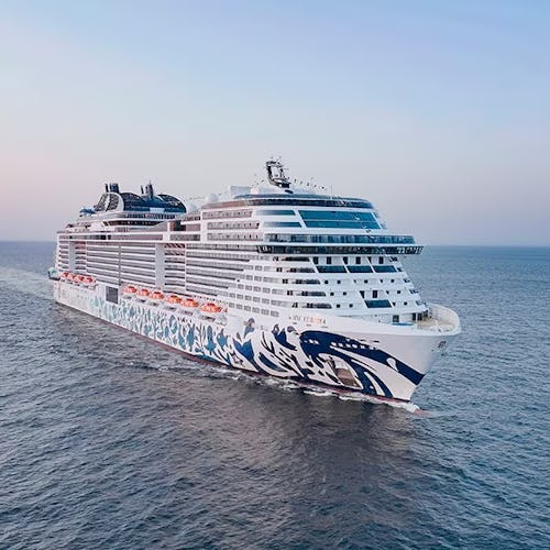 Large white cruise ship sailing across calm ocean waters at sunset.